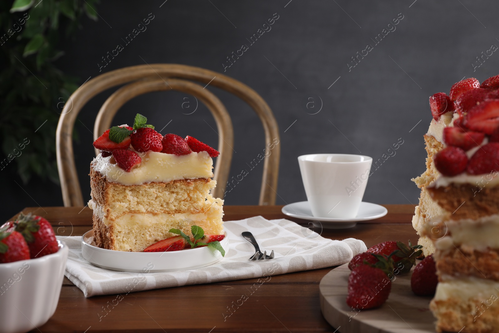 Photo of Tasty cake with fresh strawberries, mint and cup of drink on wooden table