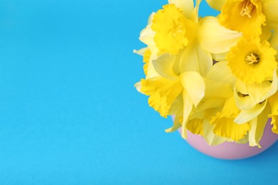Photo of Bouquet of beautiful yellow daffodils in vase on light blue background, above view. Space for text