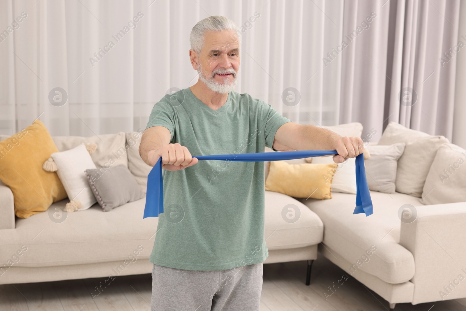 Photo of Senior man doing exercise with fitness elastic band at home