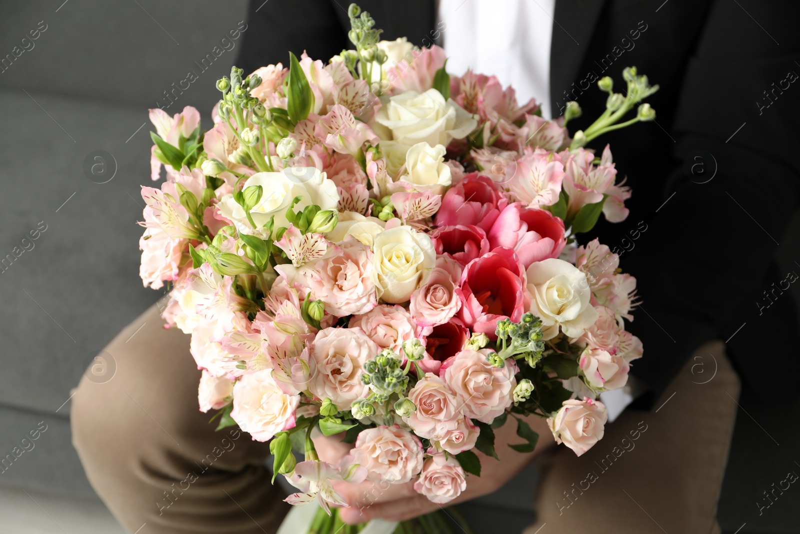 Photo of Man with beautiful bouquet of flowers on sofa indoors, closeup