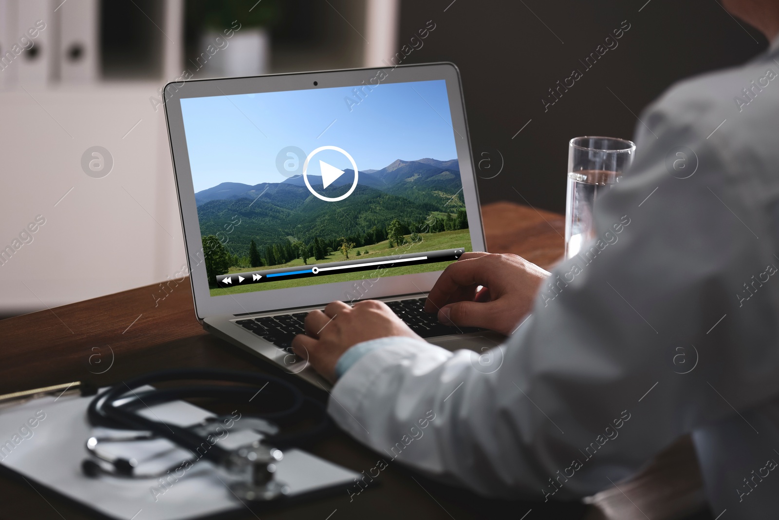 Image of Doctor watching video on laptop at office desk, closeup. Man choosing vacation spots