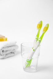 Light green toothbrush in glass holder on white background