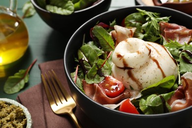 Photo of Delicious burrata salad served on green wooden table, closeup