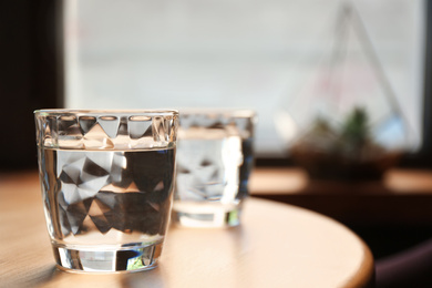 Glasses of water on wooden table in cafe. Space for text