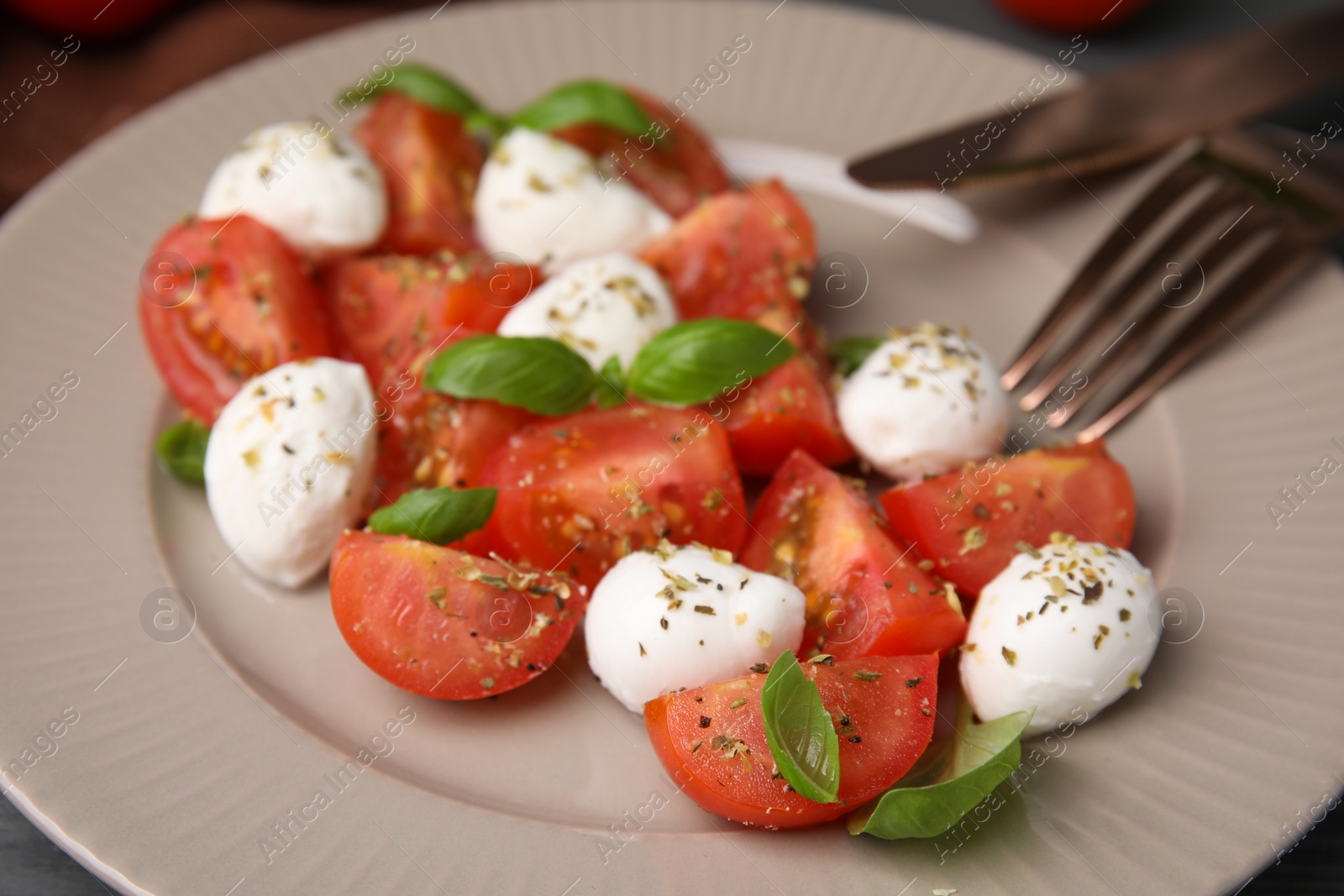 Photo of Tasty salad Caprese with mozarella balls, tomatoes and basil on plate, closeup