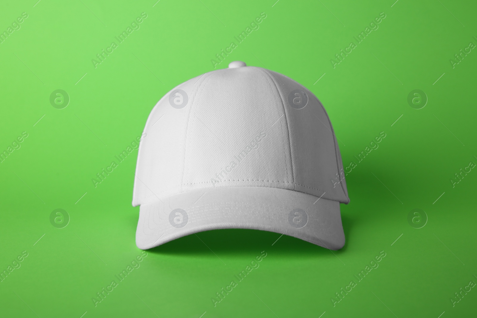 Photo of Stylish white baseball cap on light green background