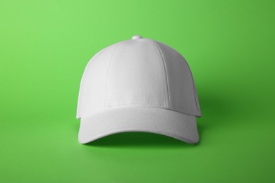 Stylish white baseball cap on light green background