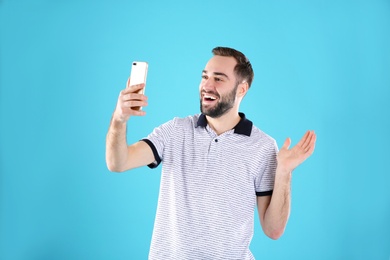 Photo of Man using mobile phone for video chat on color background