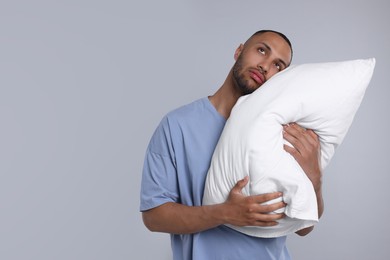 Photo of Sleepy man with pillow on light grey background, space for text. Insomnia problem