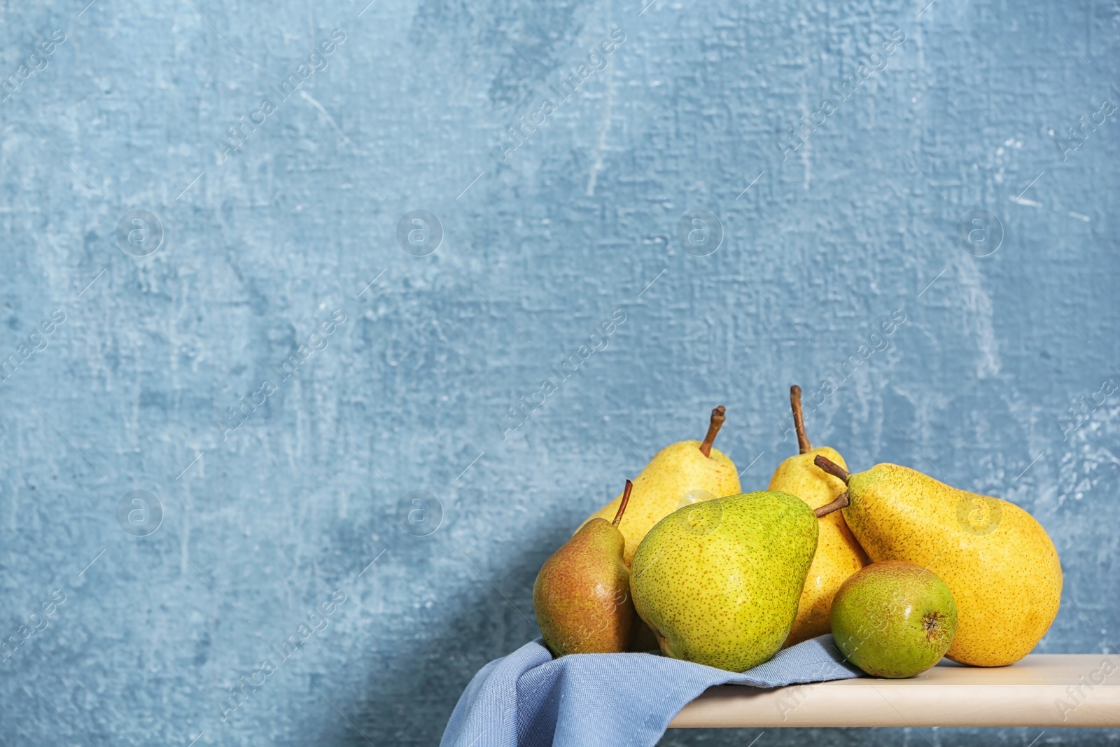 Photo of Fresh ripe pears on table against color background. Space for text