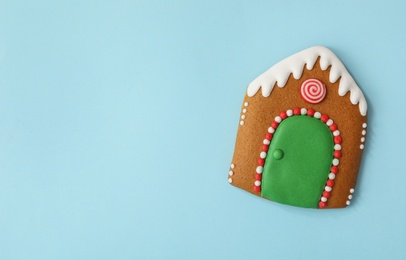 Photo of Christmas house shaped gingerbread cookie on light blue background, top view. Space for text
