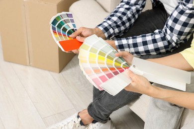Photo of Couple with paint chips choosing colors in new apartment, closeup. Moving day