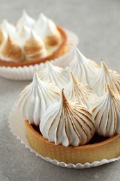 Delicious dessert. Tartlets with meringue on light grey table, closeup