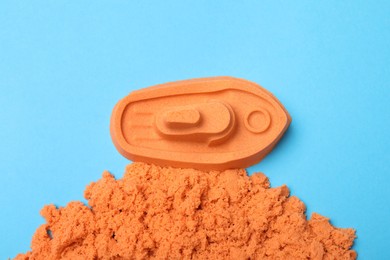 Photo of Orange kinetic sand on light blue background, flat lay