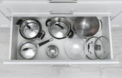 Photo of Open drawer with pots and pan indoors, top view. Order in kitchen