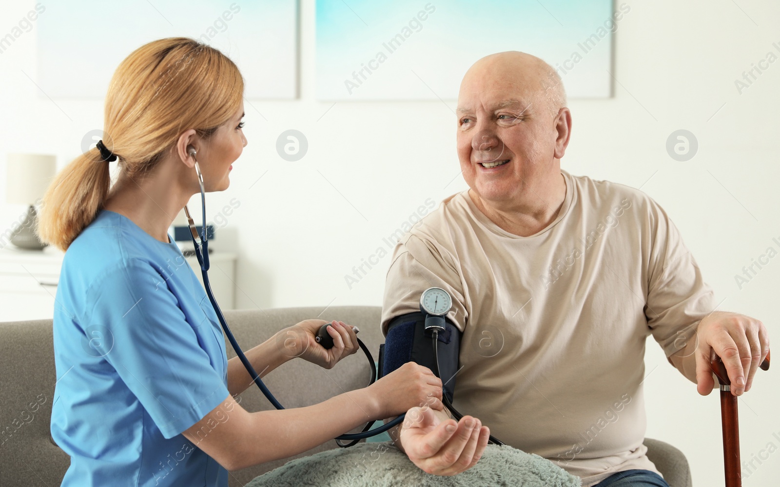 Photo of Nurse measuring blood pressure of elderly man indoors. Assisting senior people