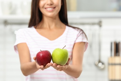 Photo of Woman holding fresh apples in kitchen, closeup