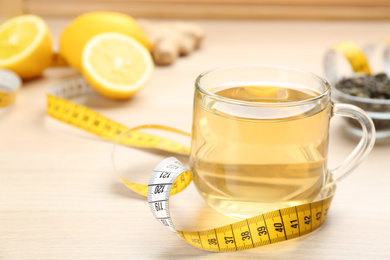 Diet herbal tea and measuring tape on wooden table