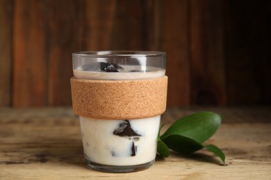 Photo of Glass of milk with grass jelly and green leaves on wooden table, closeup