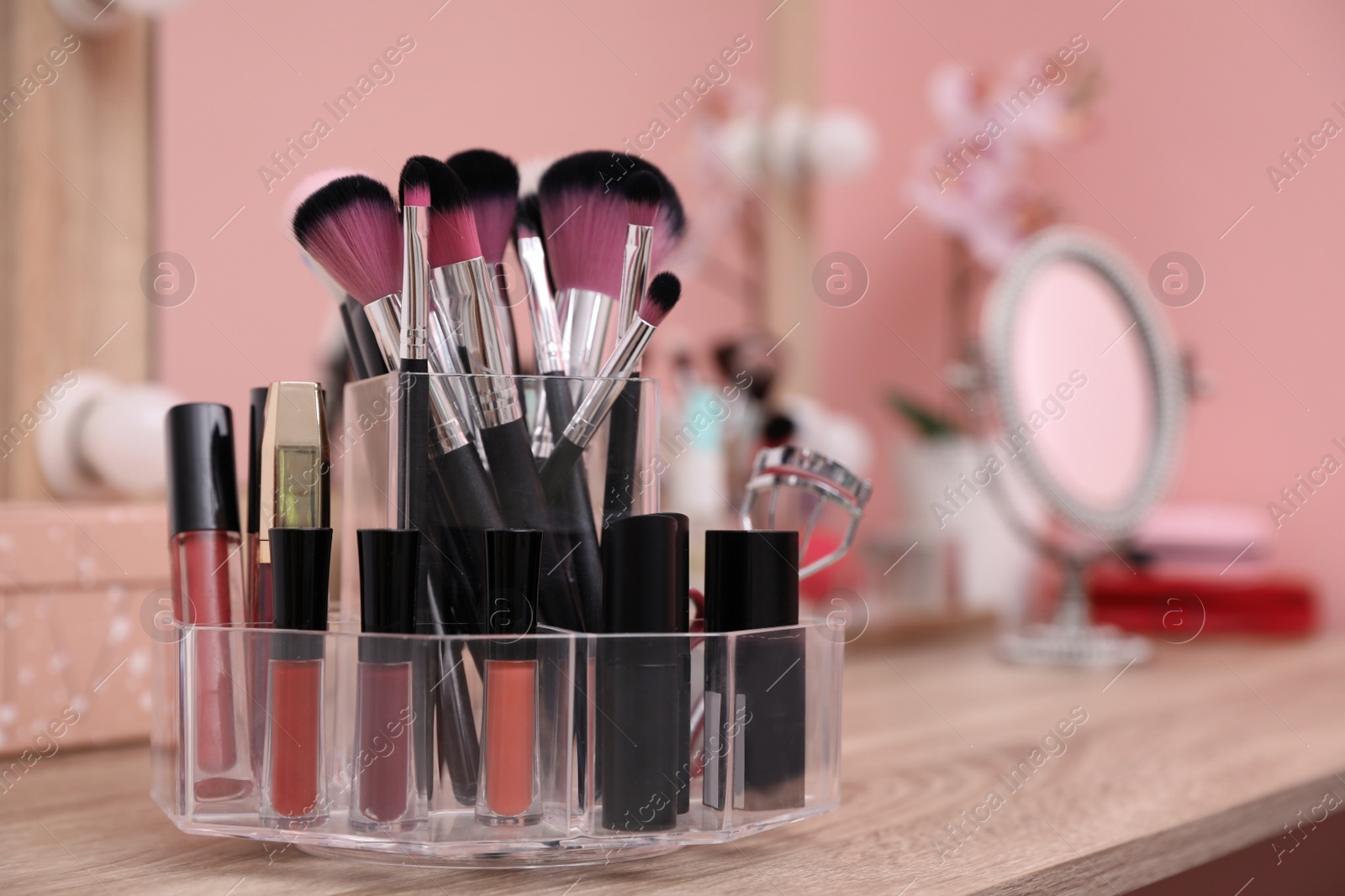 Photo of Organizer with cosmetic products for makeup on table near mirror. Space for text