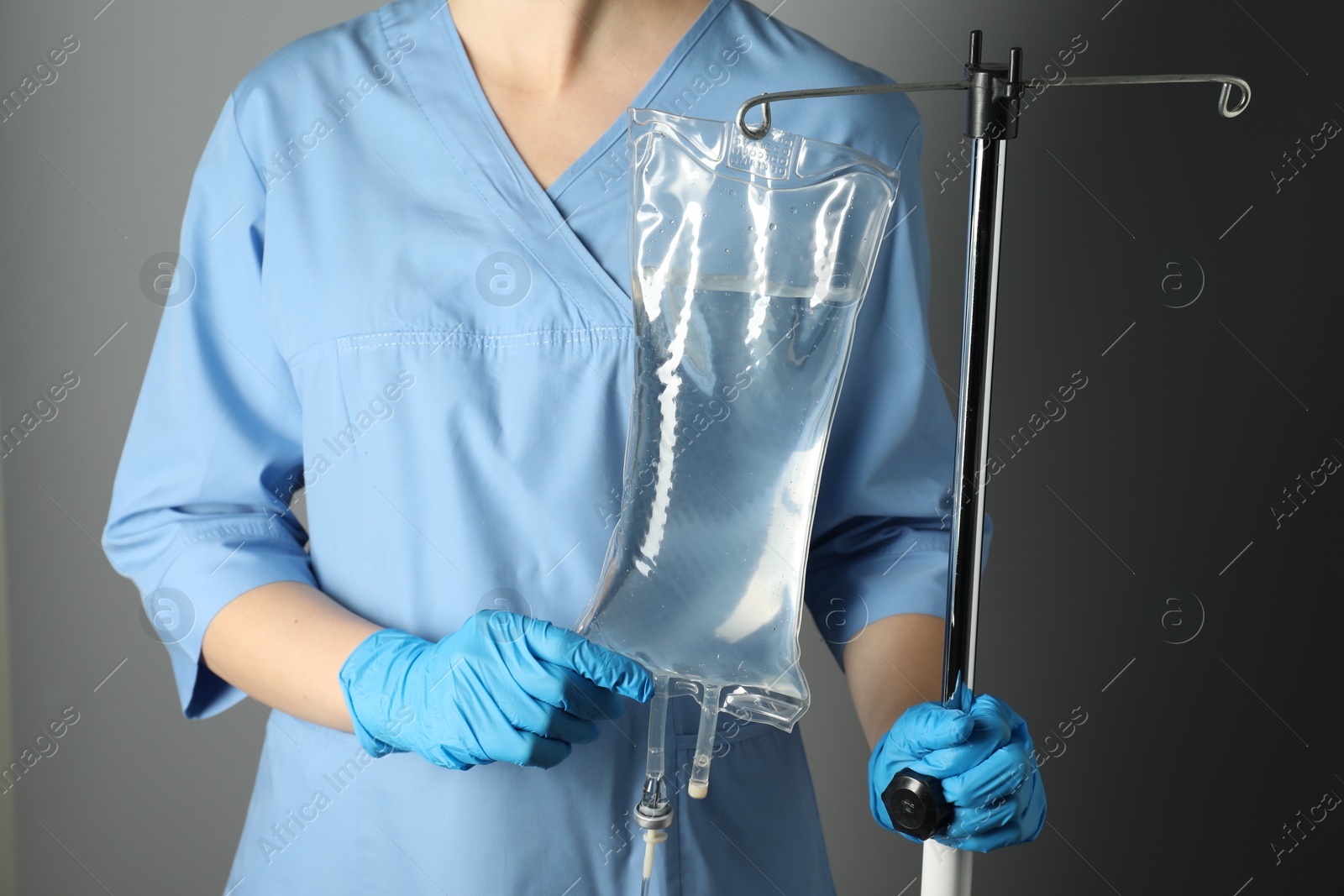 Photo of Nurse with IV infusion set on grey background, closeup