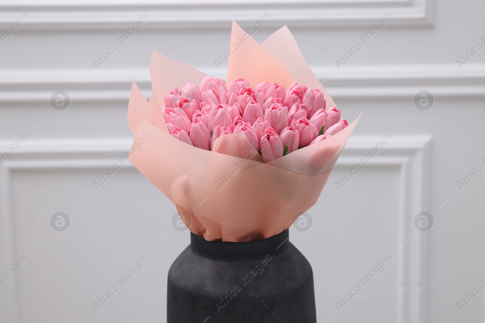 Photo of Bouquet of beautiful pink tulips near white wall
