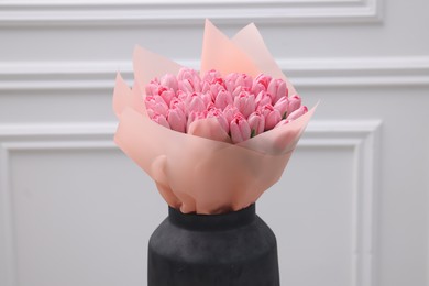 Bouquet of beautiful pink tulips near white wall