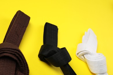 Photo of Colorful karate belts on yellow background. Martial arts uniform