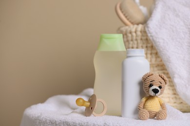 Baby cosmetic products, toy bear and pacifier on beige background. Space for text