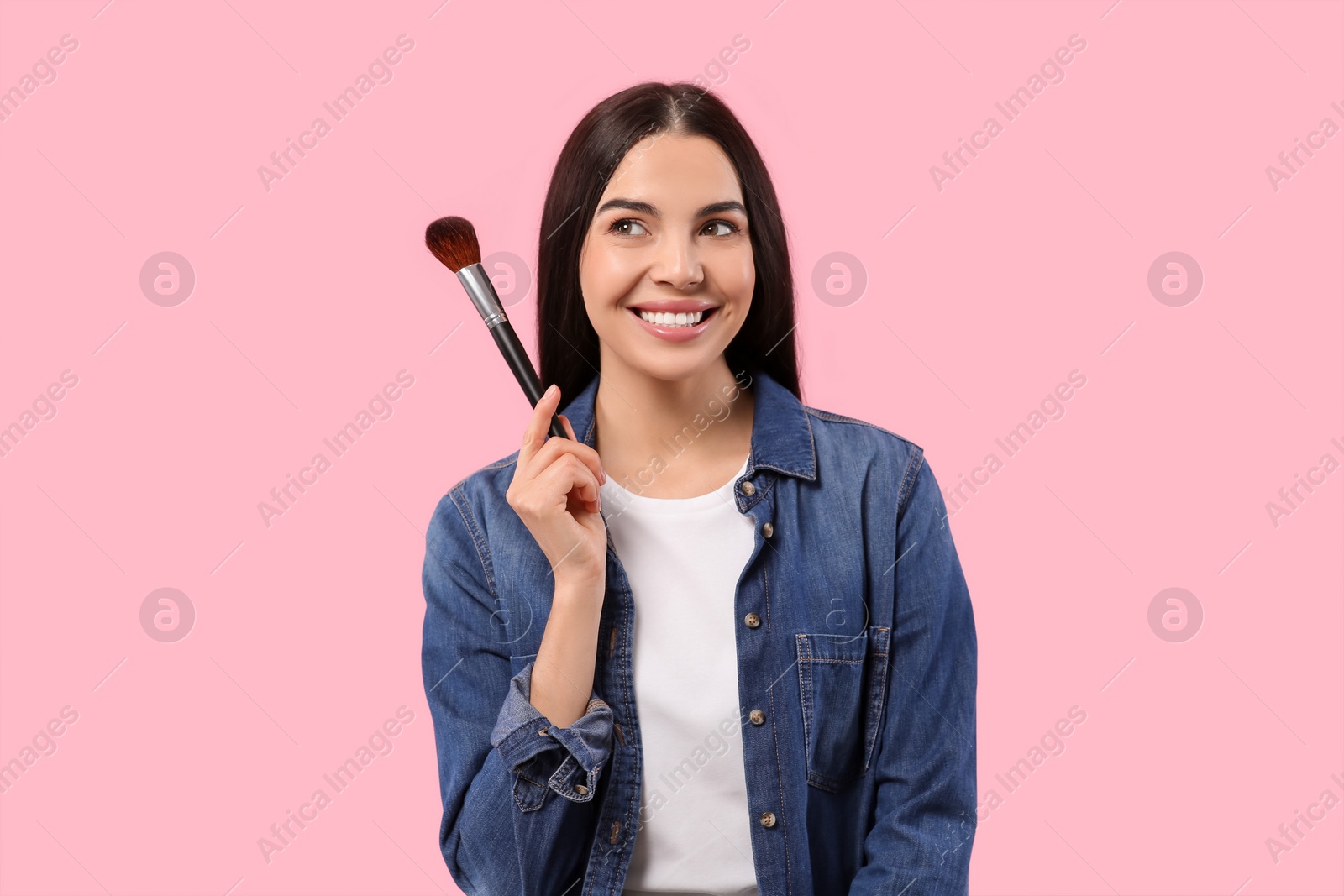 Photo of Beautiful woman with makeup brush on pink background