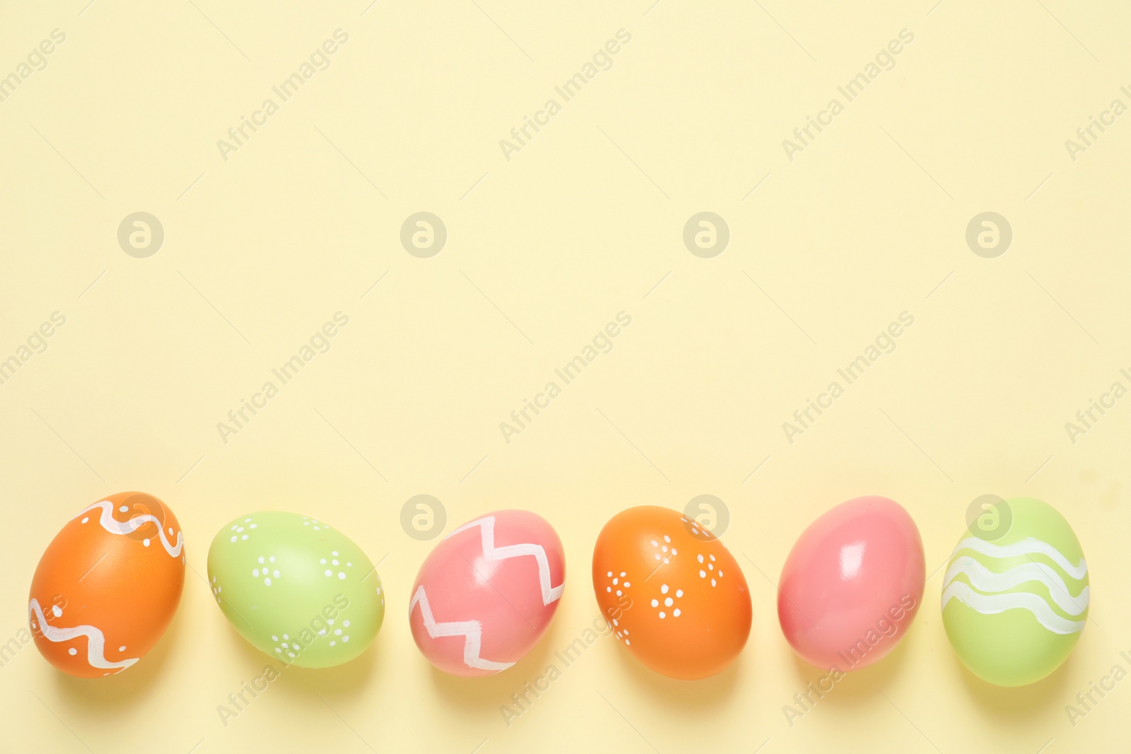 Photo of Flat lay composition of painted Easter eggs on color background, space for text