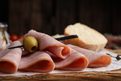 Photo of Slices of tasty ham with olive on table, closeup