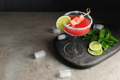 Cocktail glass of delicious fresh watermelon juice, lime, mint and ice on grey table. Space for text