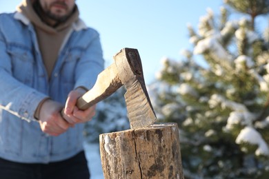 Photo of Man chopping wood with axe outdoors on winter day, closeup. Space for text