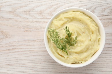 Photo of Bowl of tasty mashed potato with dill on wooden table, top view. Space for text