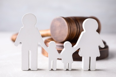 Photo of Figure in shape of people and wooden gavel on light table. Family law concept