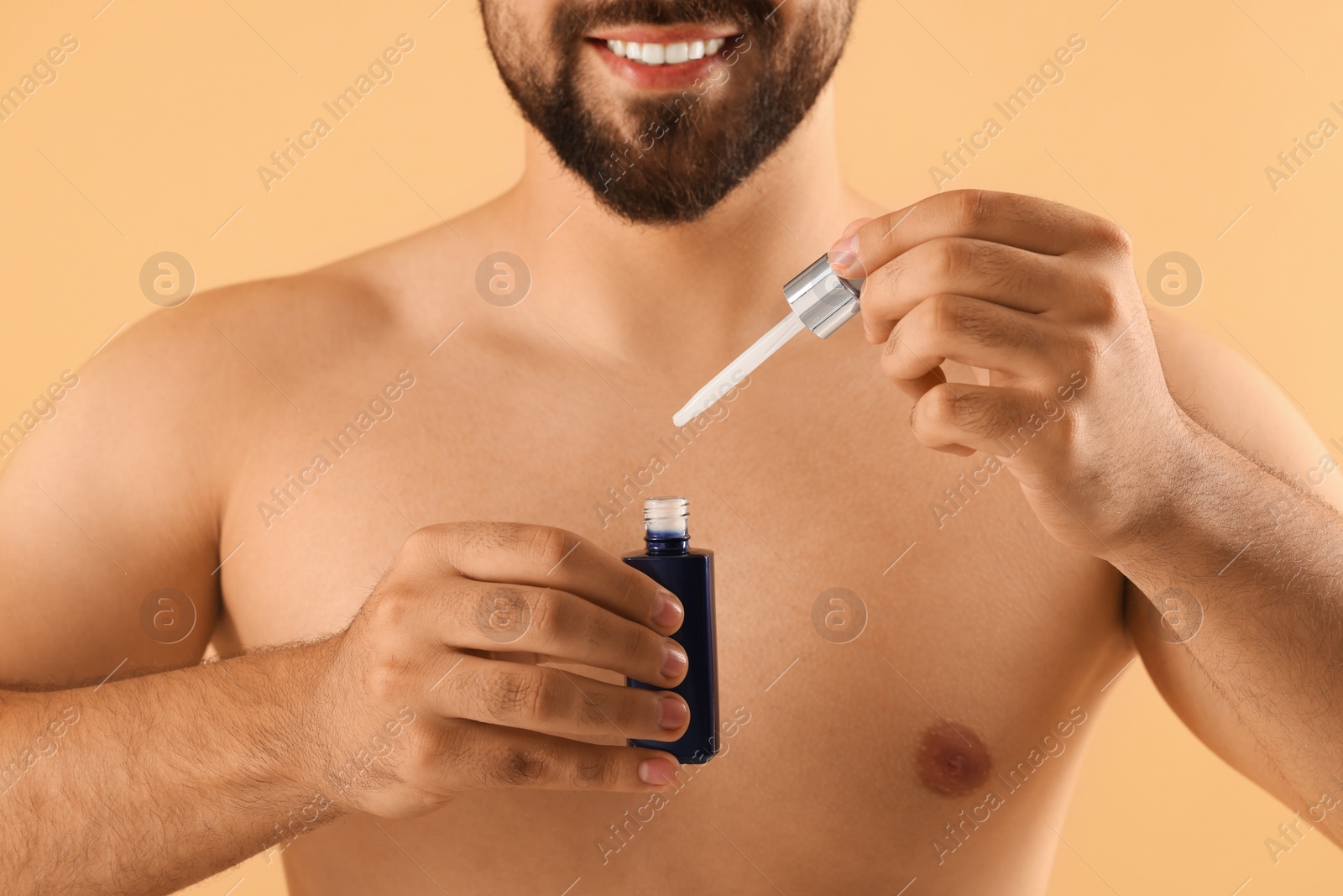 Photo of Man with cosmetic serum in hands on beige background, closeup