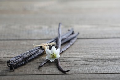 Vanilla pods and flower on wooden table, closeup. Space for text