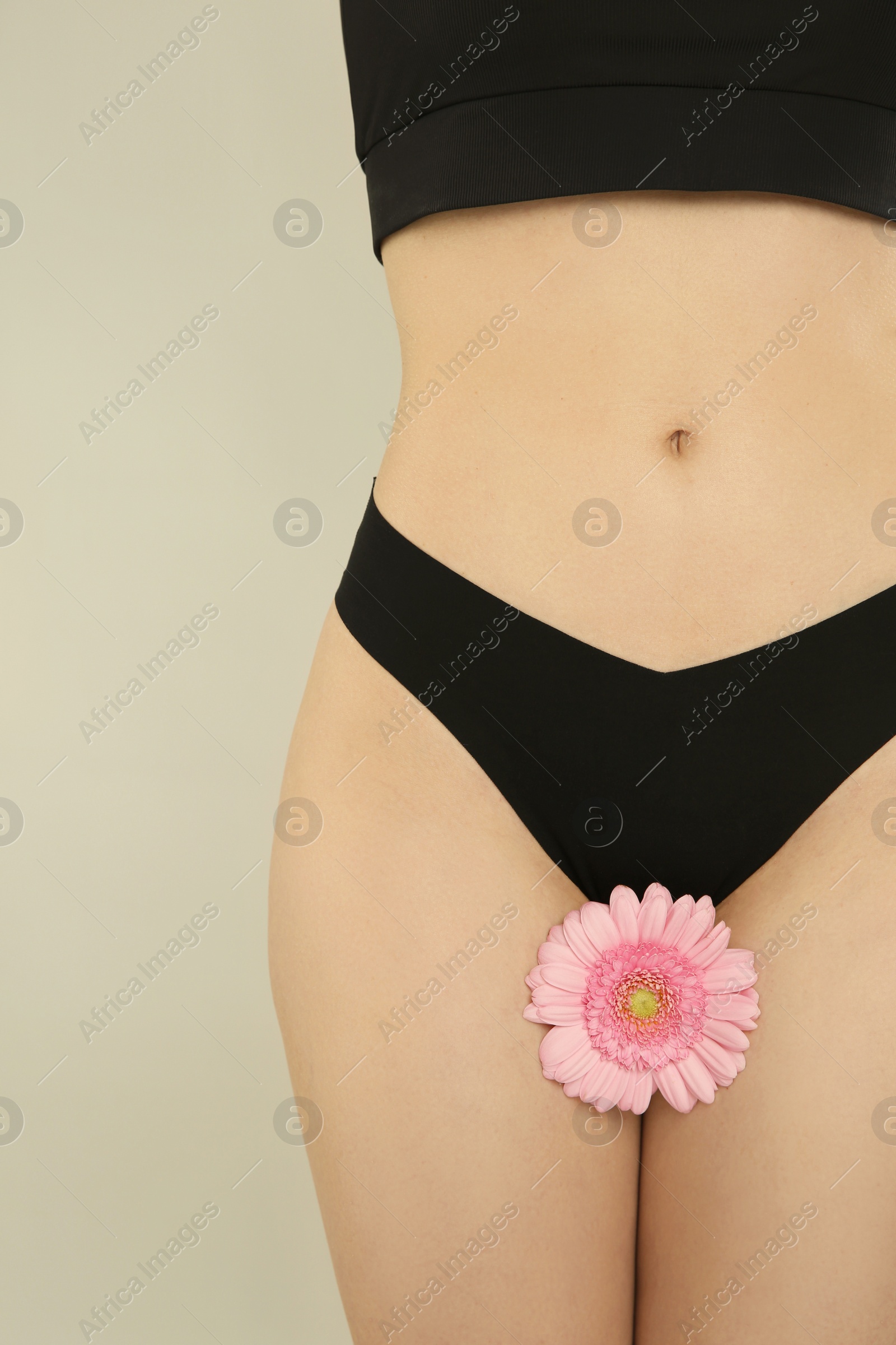 Photo of Gynecology. Woman in underwear with gerbera flower on light background, closeup