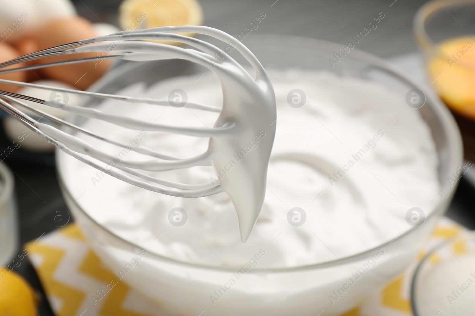 Photo of Whisk with whipped cream over bowl, closeup