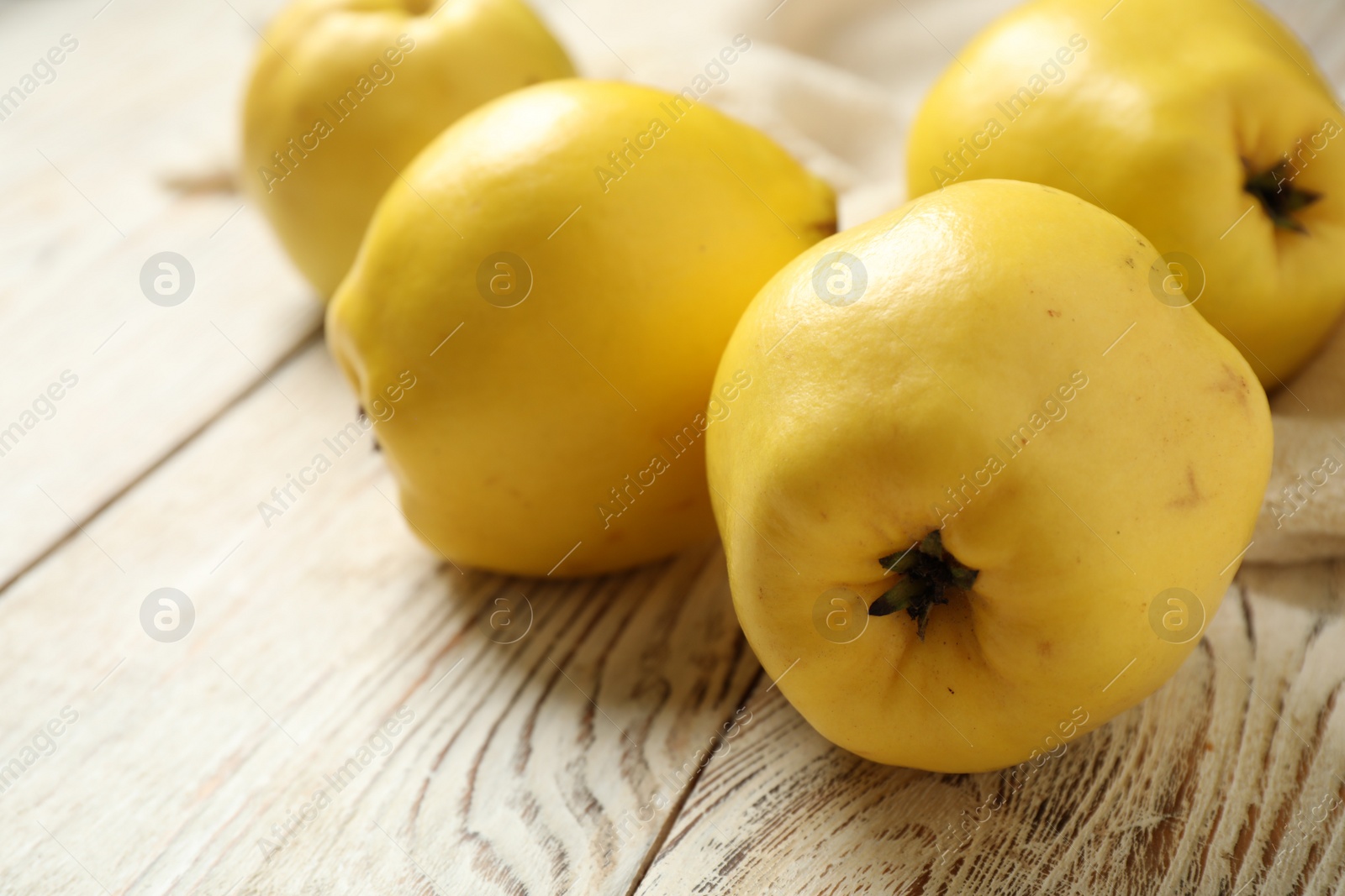 Photo of Fresh ripe organic quinces on white wooden table, closeup