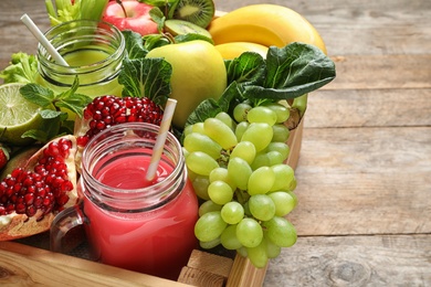 Photo of Wooden crate with juices in mason jars and fresh fruits on wooden background. Space for text