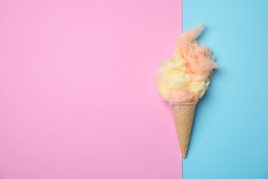 Ice cream cone with fluffy cotton candy and space for text on color background, top view