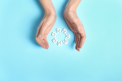 Photo of Woman holding hands near small plastic teeth on color background, top view. Space for text