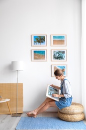 Photo of Female interior designer decorating white wall with pictures indoors