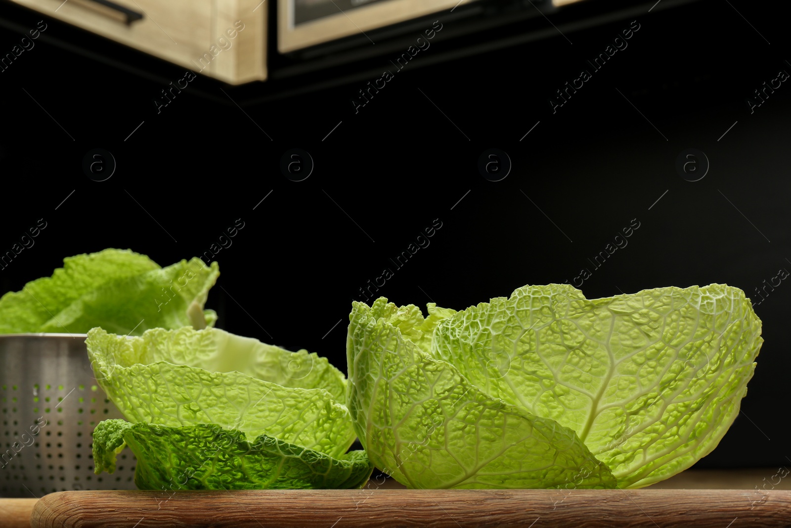 Photo of Fresh Savoy cabbage leaves on wooden board in kitchen