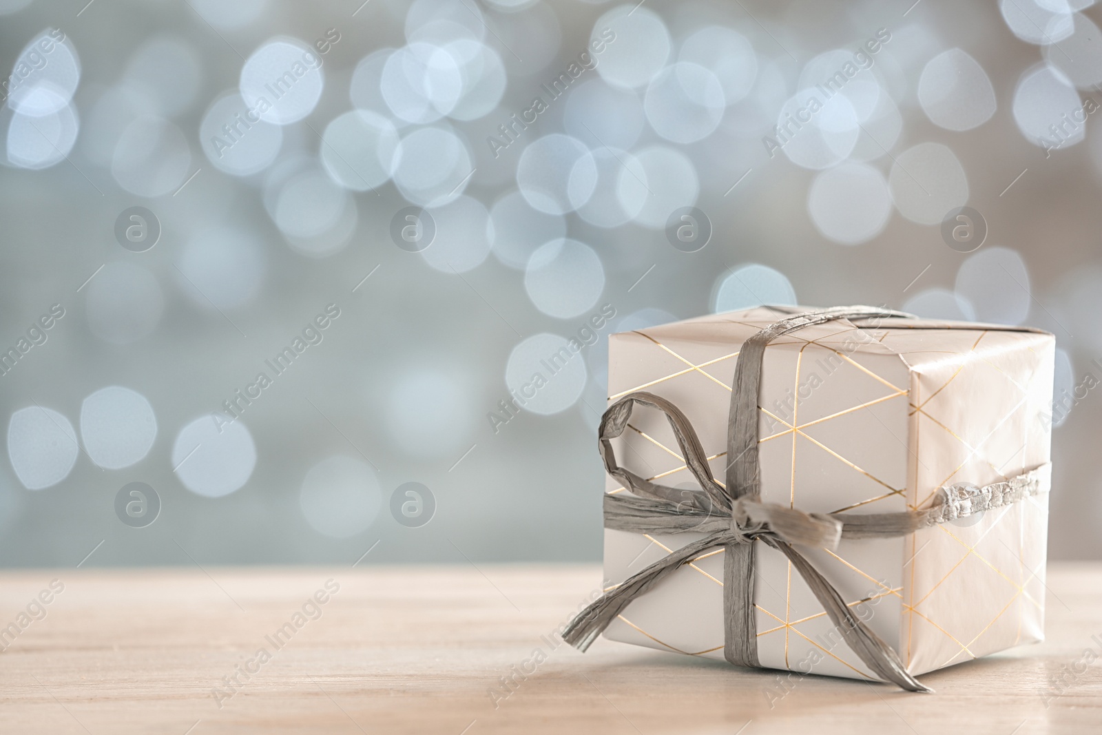 Photo of Gift box on table against blurred lights, space for text