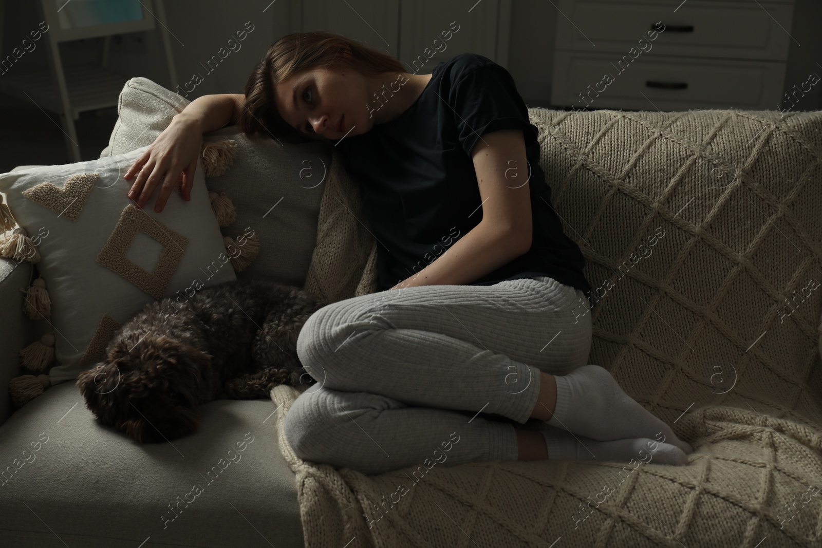 Photo of Sad young woman and her dog on sofa at home