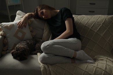Photo of Sad young woman and her dog on sofa at home