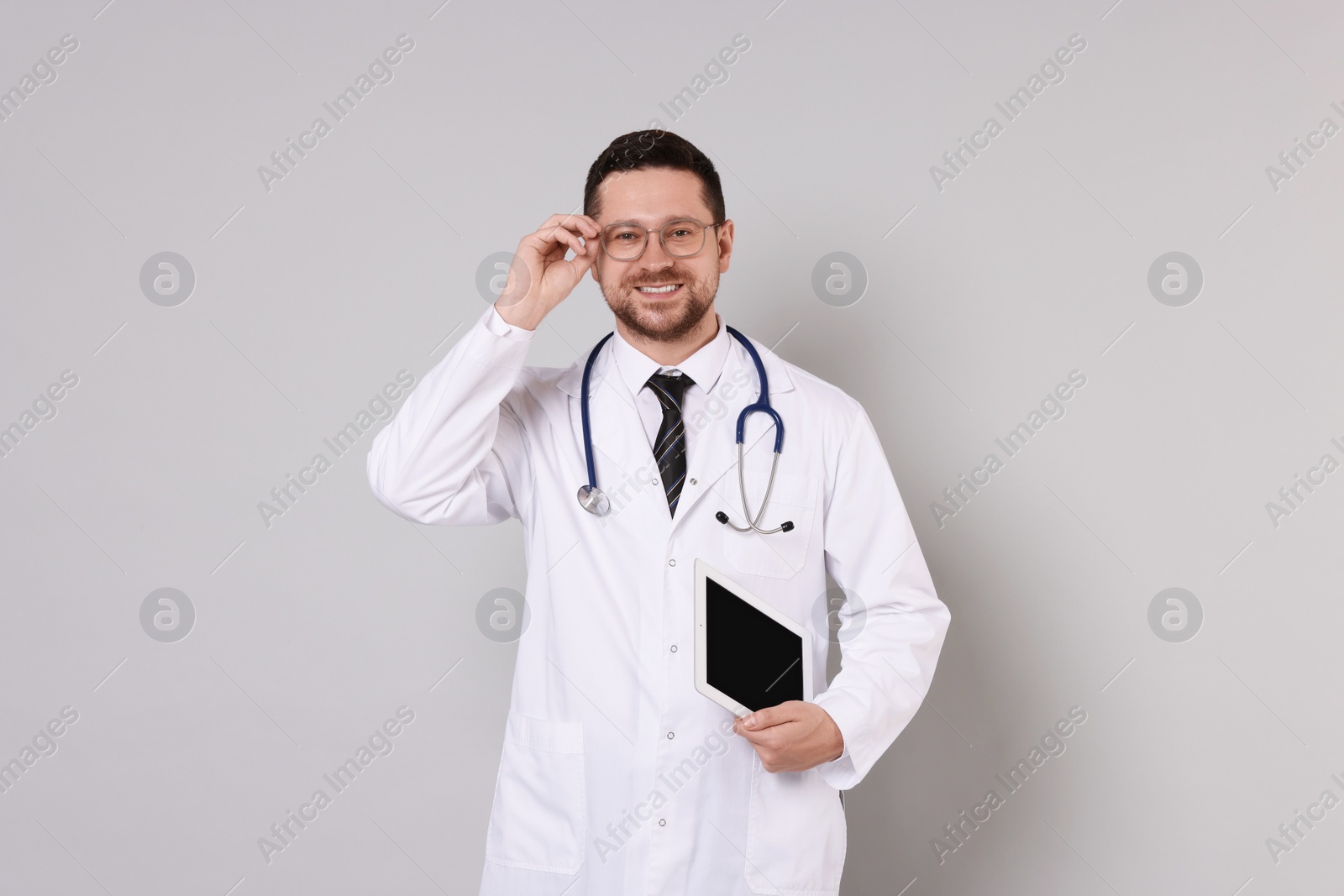 Photo of Portrait of smiling doctor with tablet on light grey background